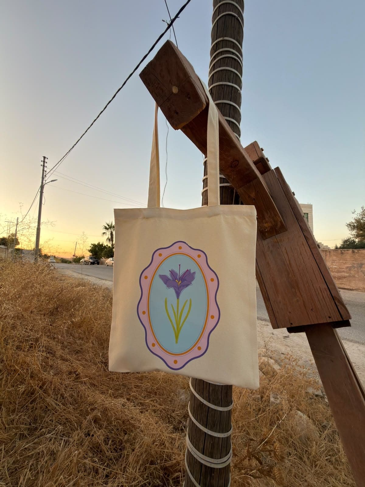 Iris canvas tote hanging from a wooden post at sunset