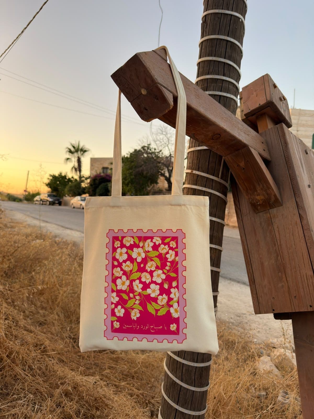 Jasmine canvas tote hanging from a wooden post at sunset